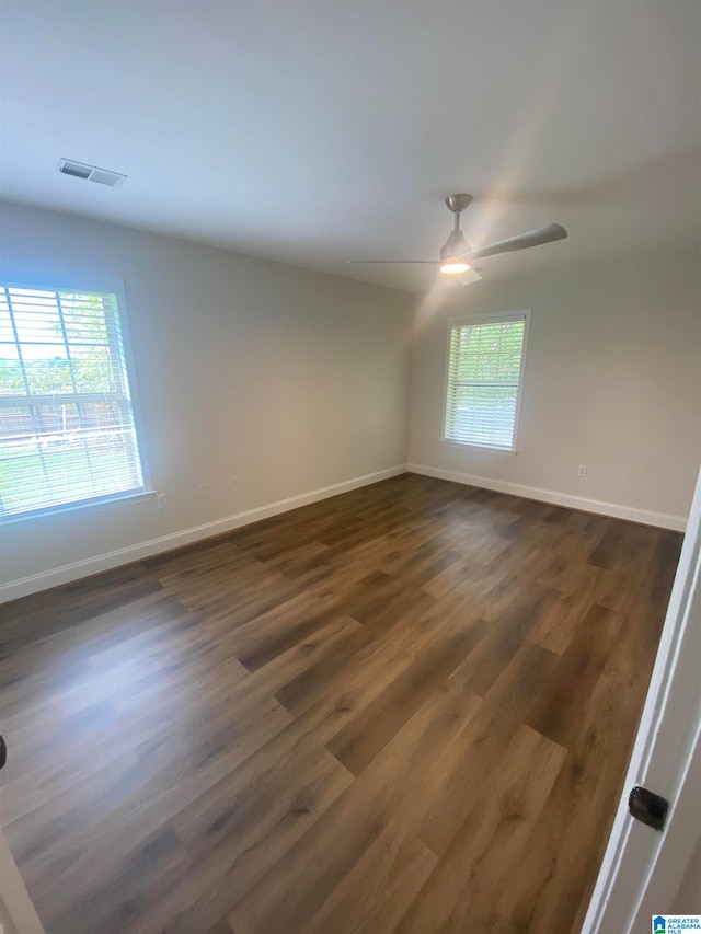 empty room featuring ceiling fan, a healthy amount of sunlight, and dark hardwood / wood-style floors