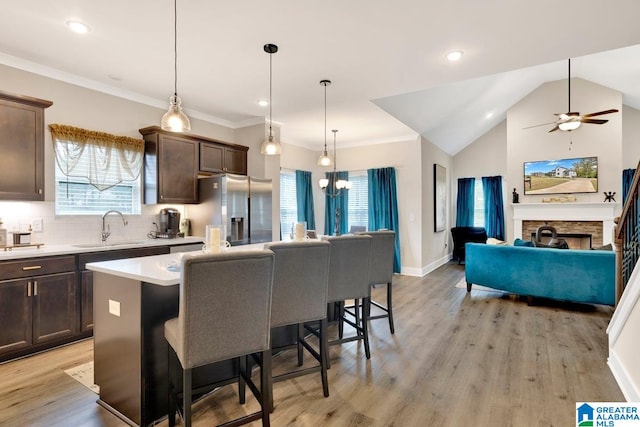 kitchen featuring stainless steel fridge, sink, a center island, pendant lighting, and light wood-type flooring