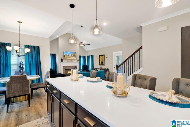 kitchen with lofted ceiling, a stone fireplace, light hardwood / wood-style flooring, and hanging light fixtures