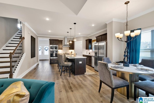 dining room with sink, crown molding, light hardwood / wood-style flooring, and an inviting chandelier