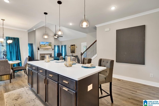 kitchen with lofted ceiling, a kitchen island, pendant lighting, and light hardwood / wood-style floors