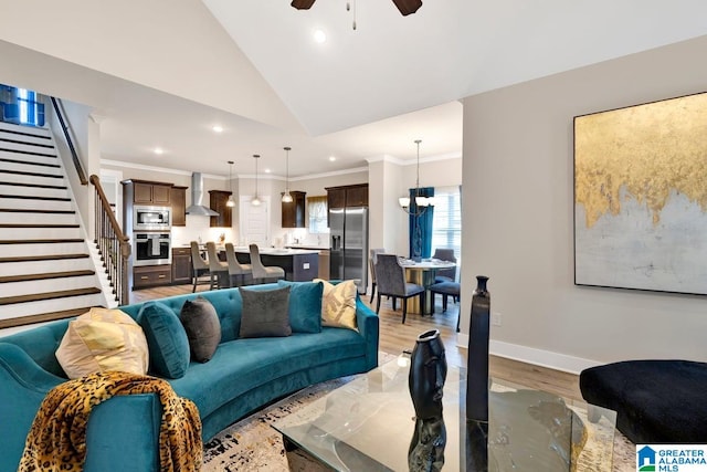 living room with crown molding, lofted ceiling, light wood-type flooring, and ceiling fan with notable chandelier