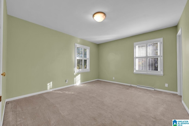 carpeted empty room featuring a baseboard heating unit