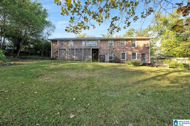 rear view of house featuring a wooden deck and a lawn