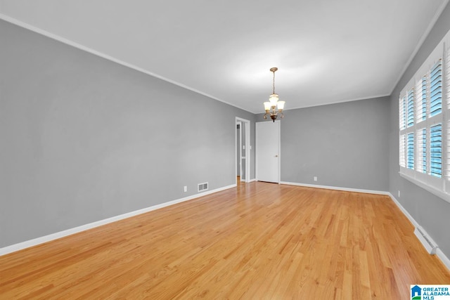 spare room featuring light wood-type flooring, a notable chandelier, and crown molding