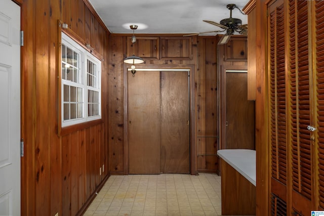 doorway featuring ornamental molding, wood walls, and ceiling fan