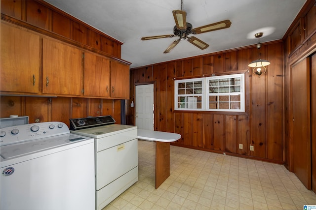 clothes washing area with ornamental molding, cabinets, wooden walls, washing machine and clothes dryer, and ceiling fan