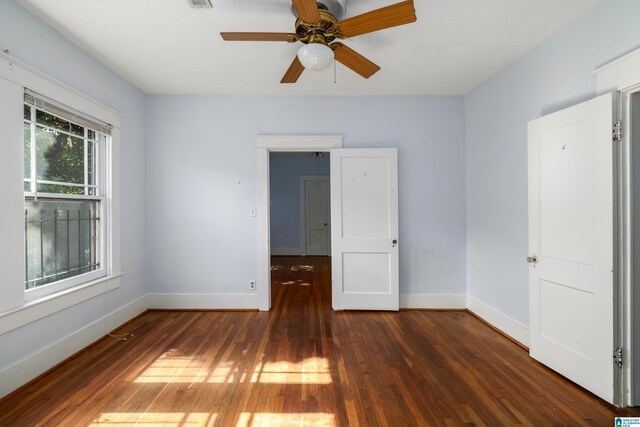 empty room featuring hardwood / wood-style flooring, visible vents, baseboards, and ceiling fan