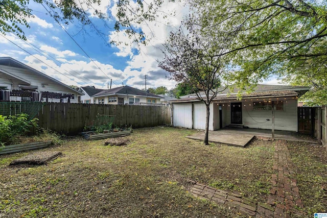 view of yard featuring a patio, a fenced backyard, and a garden