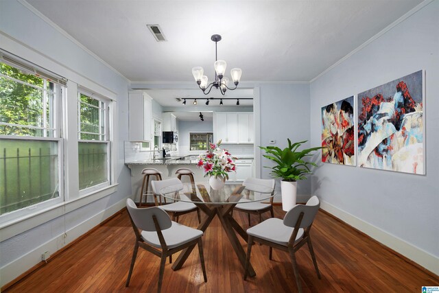 dining space featuring dark hardwood / wood-style flooring, a notable chandelier, and crown molding