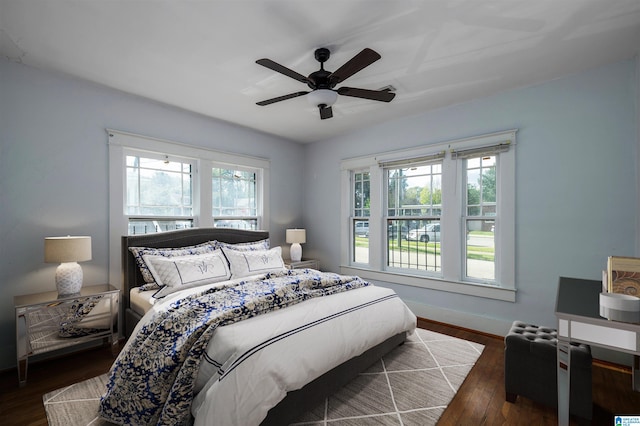 bedroom with ceiling fan, multiple windows, and dark hardwood / wood-style flooring