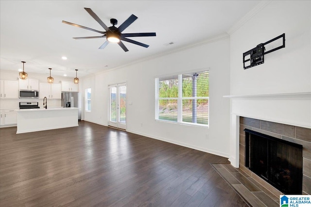 unfurnished living room featuring sink, dark hardwood / wood-style floors, ceiling fan, ornamental molding, and a fireplace