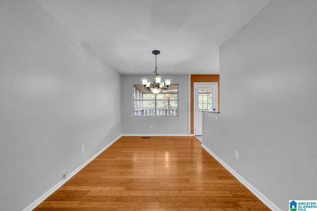 unfurnished dining area featuring a notable chandelier and light wood-type flooring