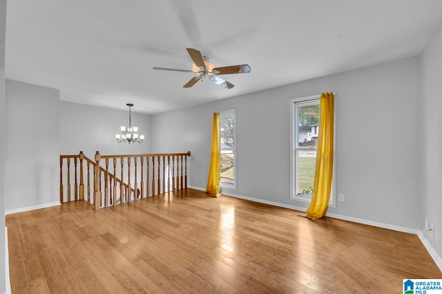 empty room with light hardwood / wood-style flooring and ceiling fan with notable chandelier