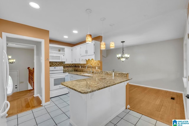 kitchen featuring white appliances, tasteful backsplash, kitchen peninsula, hanging light fixtures, and white cabinets