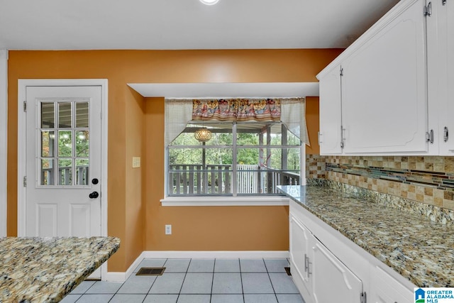 kitchen with white cabinets, a healthy amount of sunlight, tasteful backsplash, and light tile patterned floors