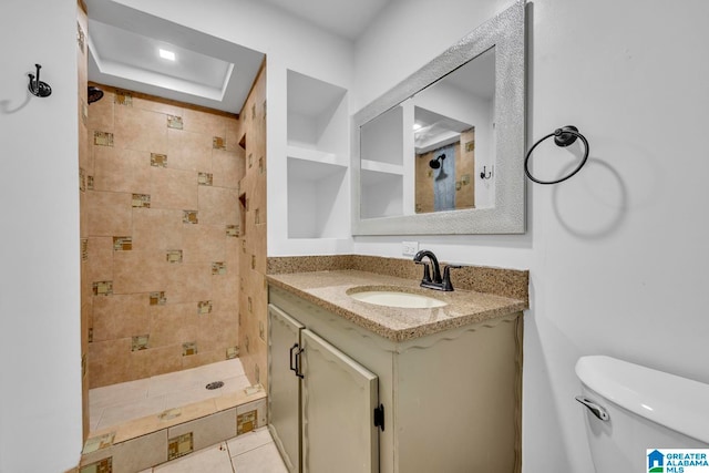 bathroom featuring vanity, toilet, a tile shower, and tile patterned flooring