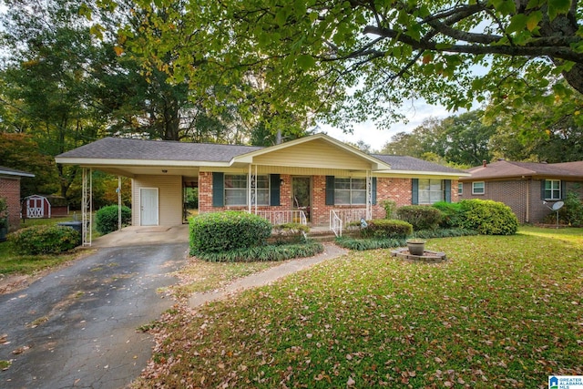 single story home featuring a front yard, a storage unit, a carport, and a porch