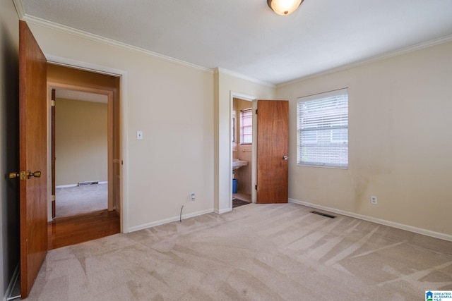 unfurnished bedroom featuring ornamental molding, ensuite bathroom, and light colored carpet