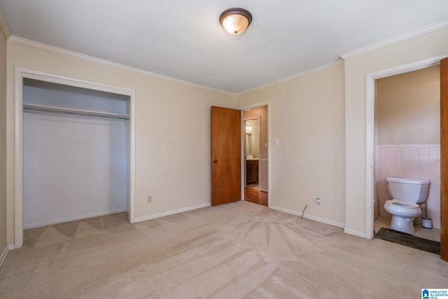 unfurnished bedroom featuring crown molding, light carpet, ensuite bathroom, and a closet