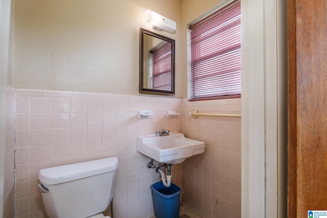 bathroom featuring toilet, sink, and tile walls