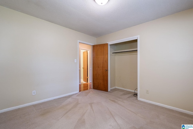 unfurnished bedroom featuring a closet, light carpet, and a textured ceiling