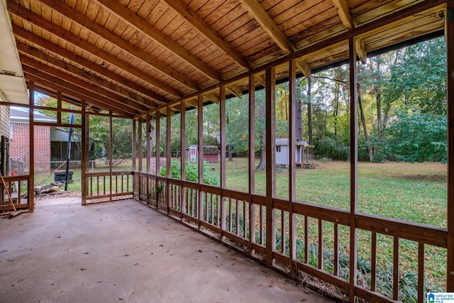 unfurnished sunroom featuring lofted ceiling with beams and wooden ceiling