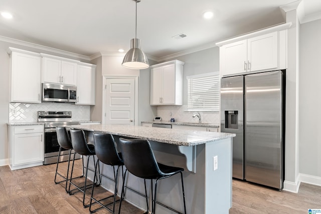 569 Avondale Ln, Pell City, AL 35128 - kitchen with stainless steel appliances, a center island, crown molding, white cabinets, and tasteful backsplash