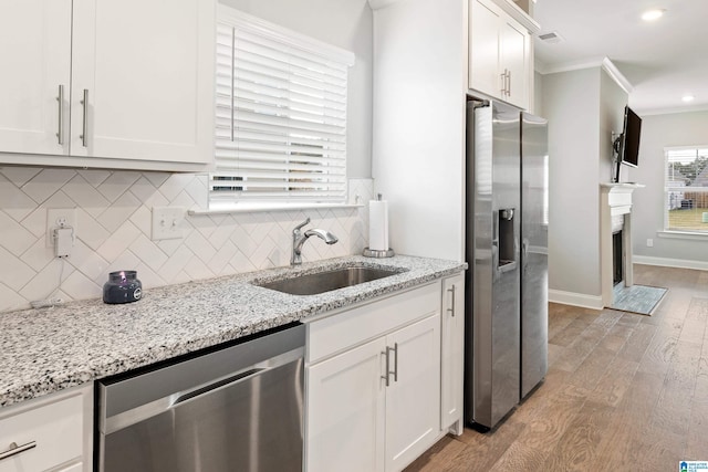 569 Avondale Ln, Pell City, AL 35128 - kitchen with appliances with stainless steel finishes, a sink, light wood-type flooring, ornamental molding, and backsplash