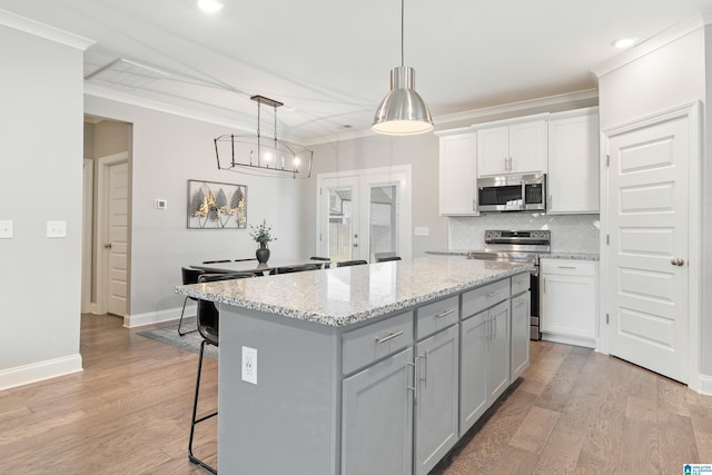 569 Avondale Ln, Pell City, AL 35128 - kitchen featuring stainless steel appliances, decorative backsplash, a center island, ornamental molding, and a breakfast bar