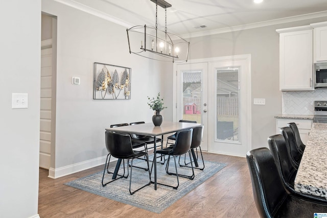 dining space featuring french doors, ornamental molding, a chandelier, and dark hardwood / wood-style flooring