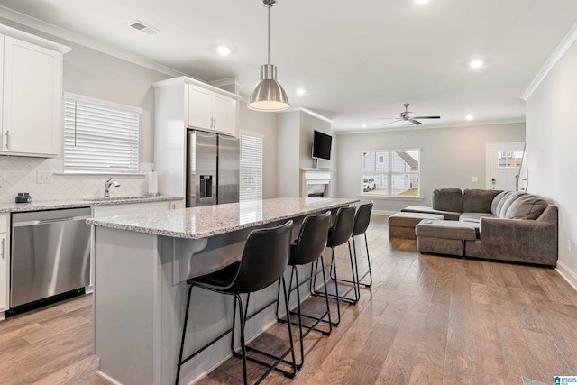 kitchen with white cabinetry, appliances with stainless steel finishes, a center island, and light wood-type flooring