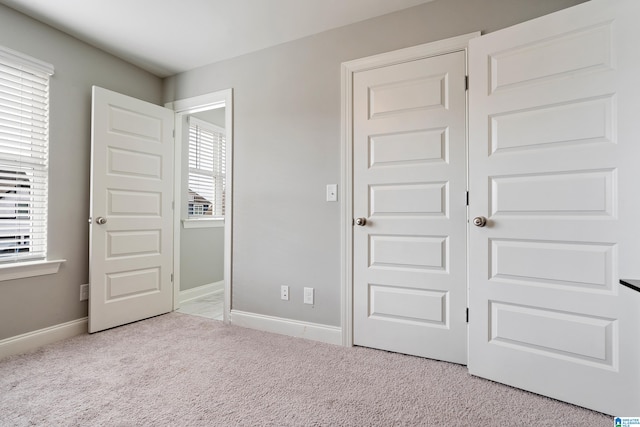 unfurnished bedroom featuring light carpet, multiple windows, and a closet