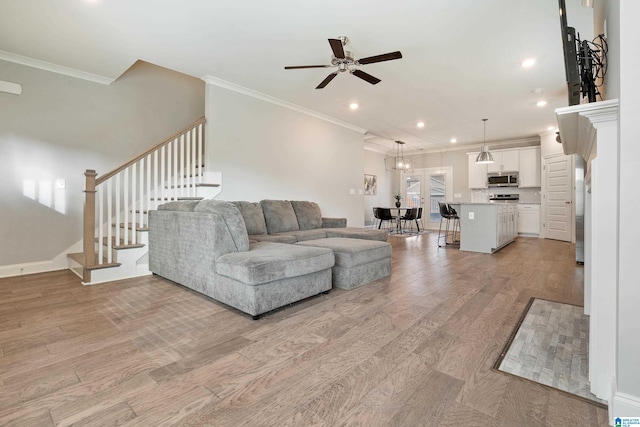 living room featuring light hardwood / wood-style floors, ornamental molding, and ceiling fan