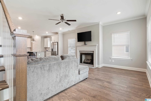 living room with light hardwood / wood-style flooring, ceiling fan, and crown molding