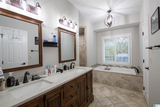 bathroom featuring a chandelier, vanity, tile patterned flooring, and tiled tub