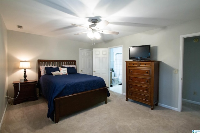 bedroom featuring light colored carpet, ceiling fan, and connected bathroom