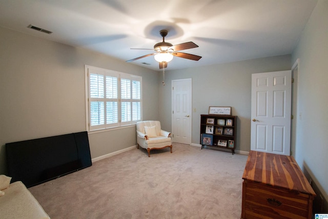 living area with light carpet and ceiling fan