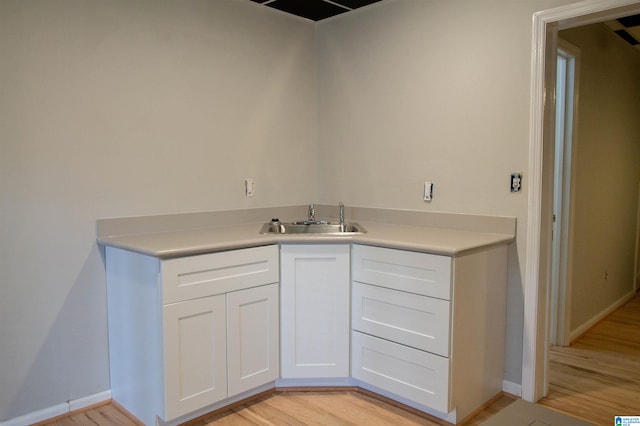 kitchen with white cabinets, light hardwood / wood-style floors, and sink