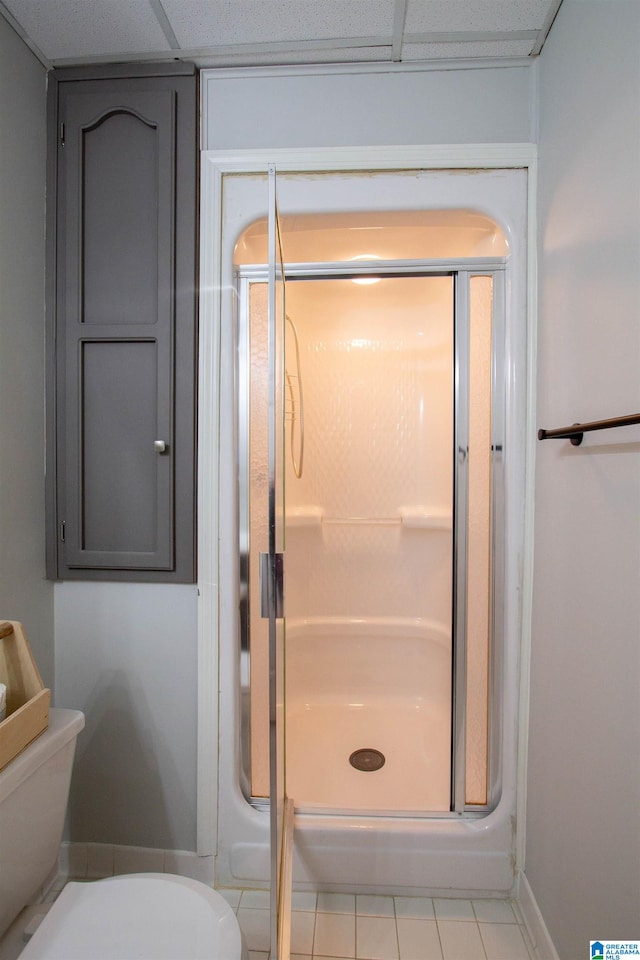 bathroom featuring walk in shower, tile patterned flooring, toilet, and a drop ceiling