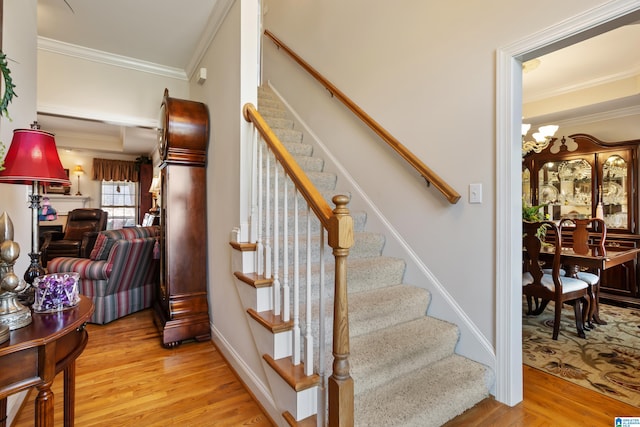 stairs with a notable chandelier, ornamental molding, and wood-type flooring