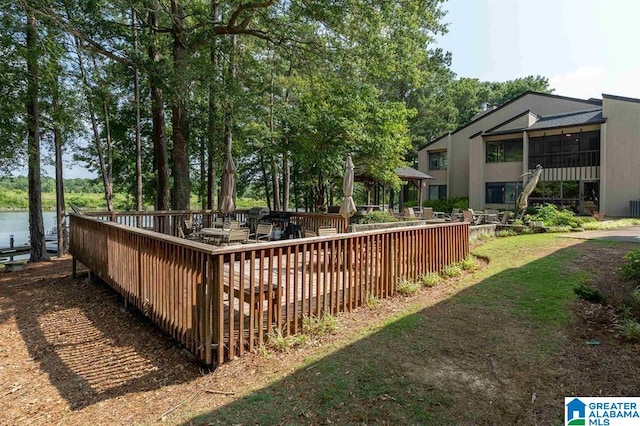 view of yard with a sunroom and a deck with water view