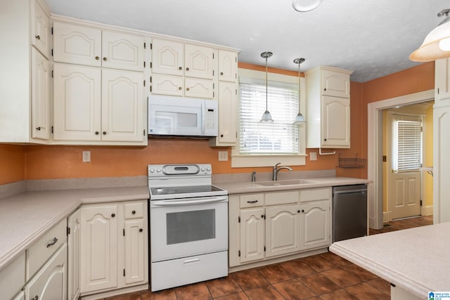 kitchen with sink, a textured ceiling, dark tile patterned floors, pendant lighting, and white appliances