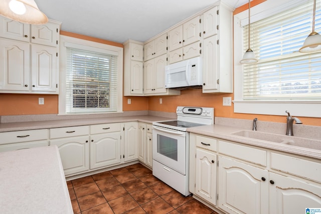 kitchen with white appliances, sink, hanging light fixtures, and white cabinets