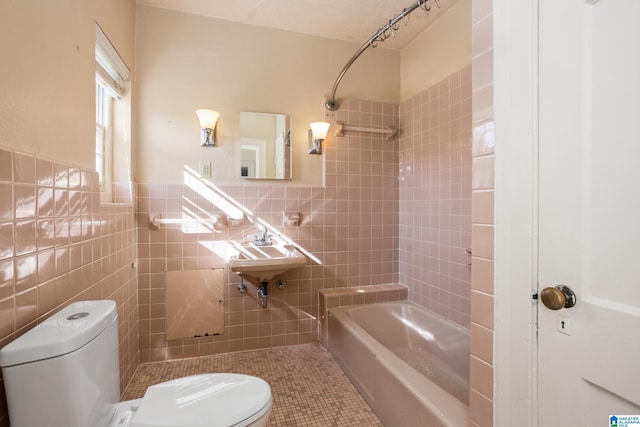 bathroom featuring tiled shower / bath, tile patterned floors, toilet, and tile walls