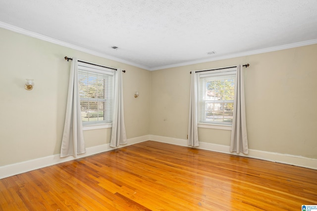 spare room featuring crown molding, light hardwood / wood-style floors, and a textured ceiling