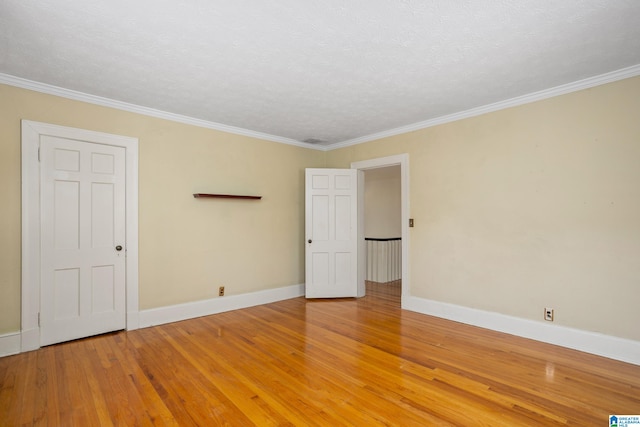 empty room with hardwood / wood-style floors, ornamental molding, and a textured ceiling