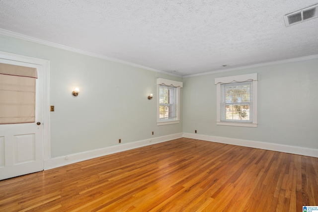 empty room with wood-type flooring, a textured ceiling, and crown molding