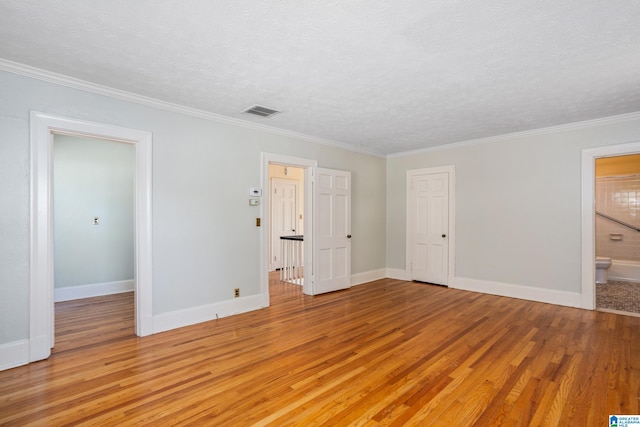 unfurnished bedroom featuring ornamental molding, a textured ceiling, light hardwood / wood-style floors, and ensuite bath