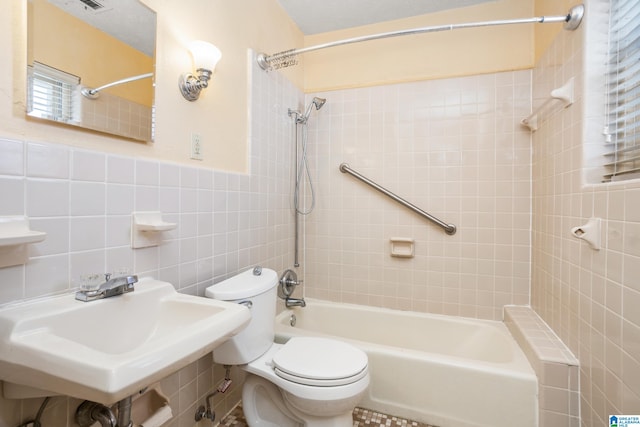 full bathroom with tile walls, sink, tiled shower / bath combo, and toilet